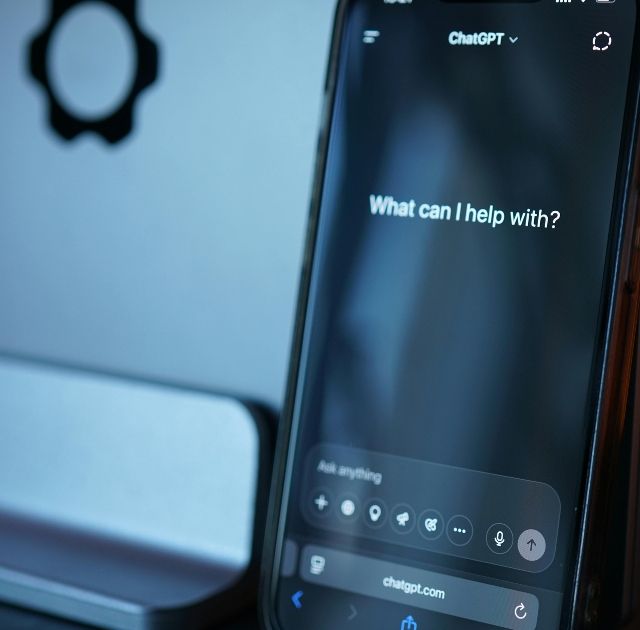En smartphone visar ChatGPT-frågan "What can I help with?" med en modern design, perfekt för webbutveckling och AI-appar